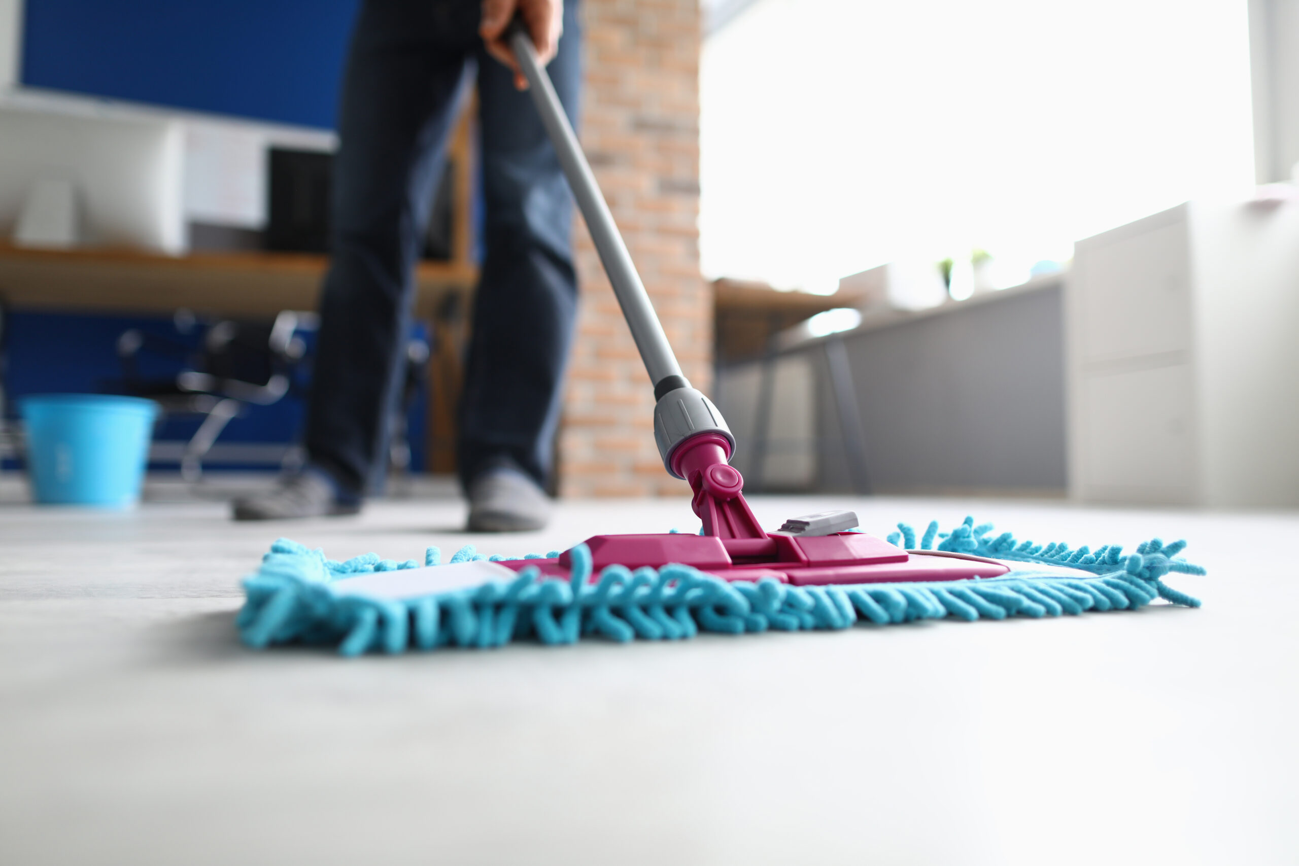 Man with mop washes floor in office closeup Agents discrets, formés et efficaces